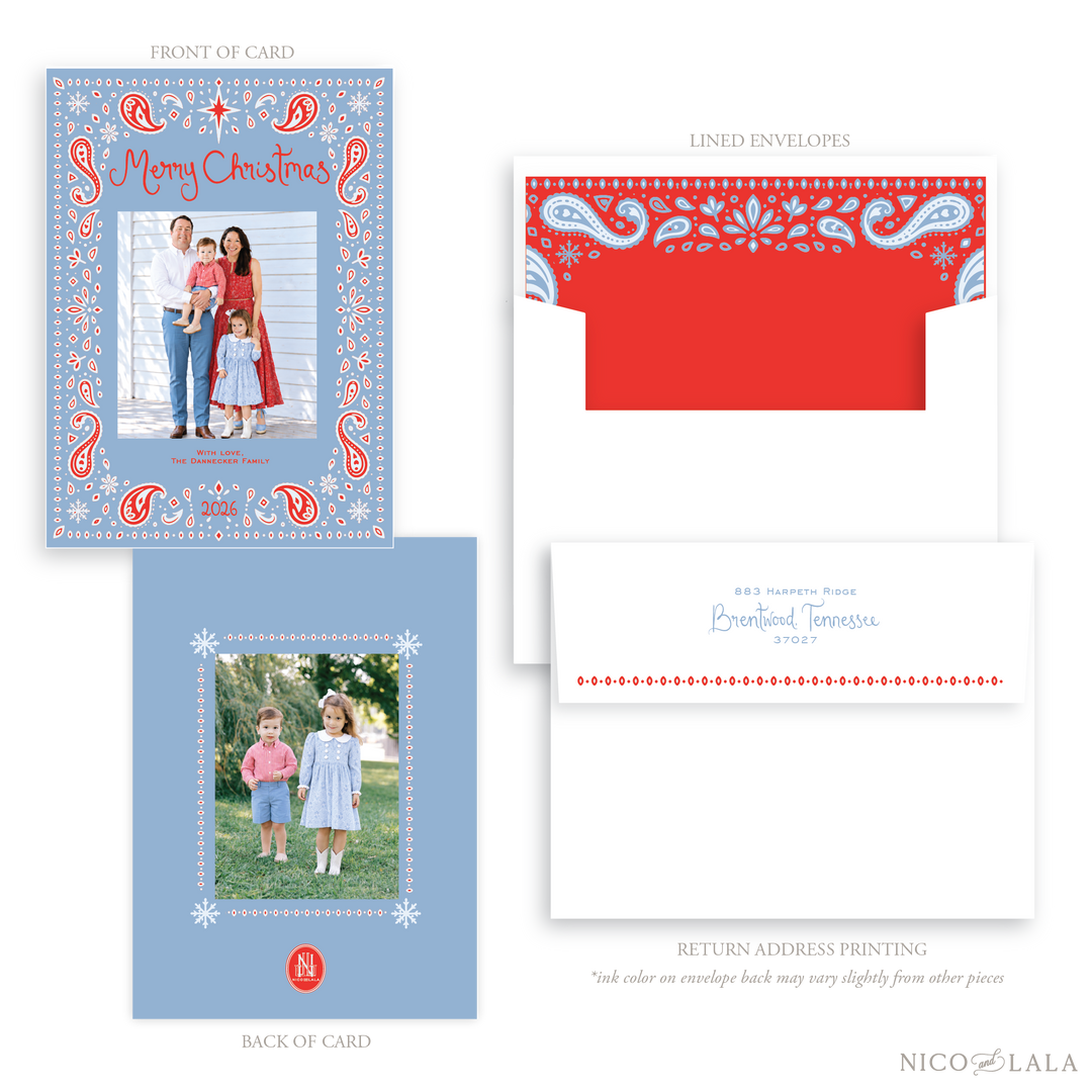 A Bandana print Christmas card and envelope set. The card is a dusty blue with a red and light blue paisley print where a customer uploads their own photo front and back. Envelope liners and return address are available as add ons. The card features red decorative text reading 'Merry Christmas'.