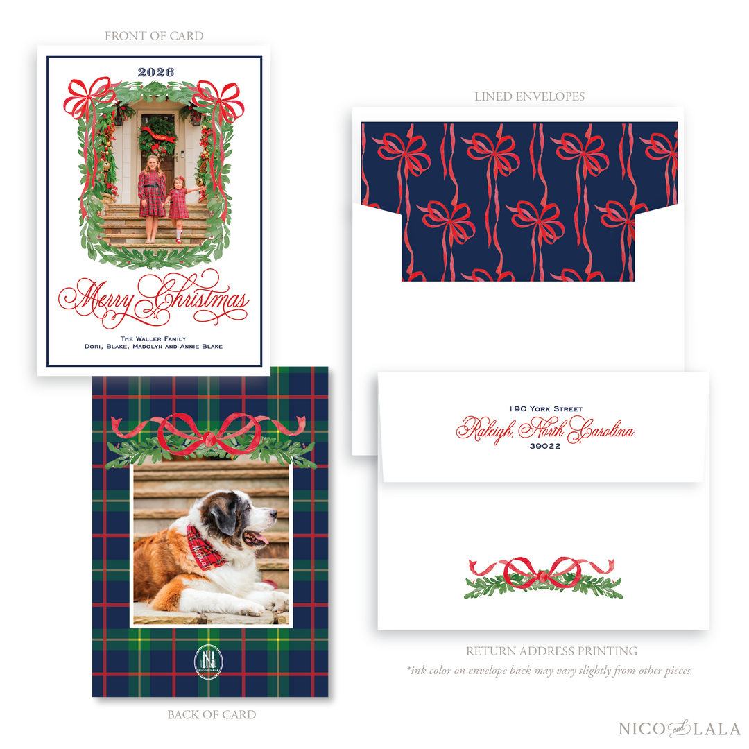 A classic Christmas card and envelope set shown on a white background, with front and back of the card, two lined envelopes, and a return address label. The card features a greenery border around the photo upload area with two red bows. The back of the card has a holiday plaid and greenery illustrations. Envelopes include a navy liner with red bow patterns and a white envelope. 