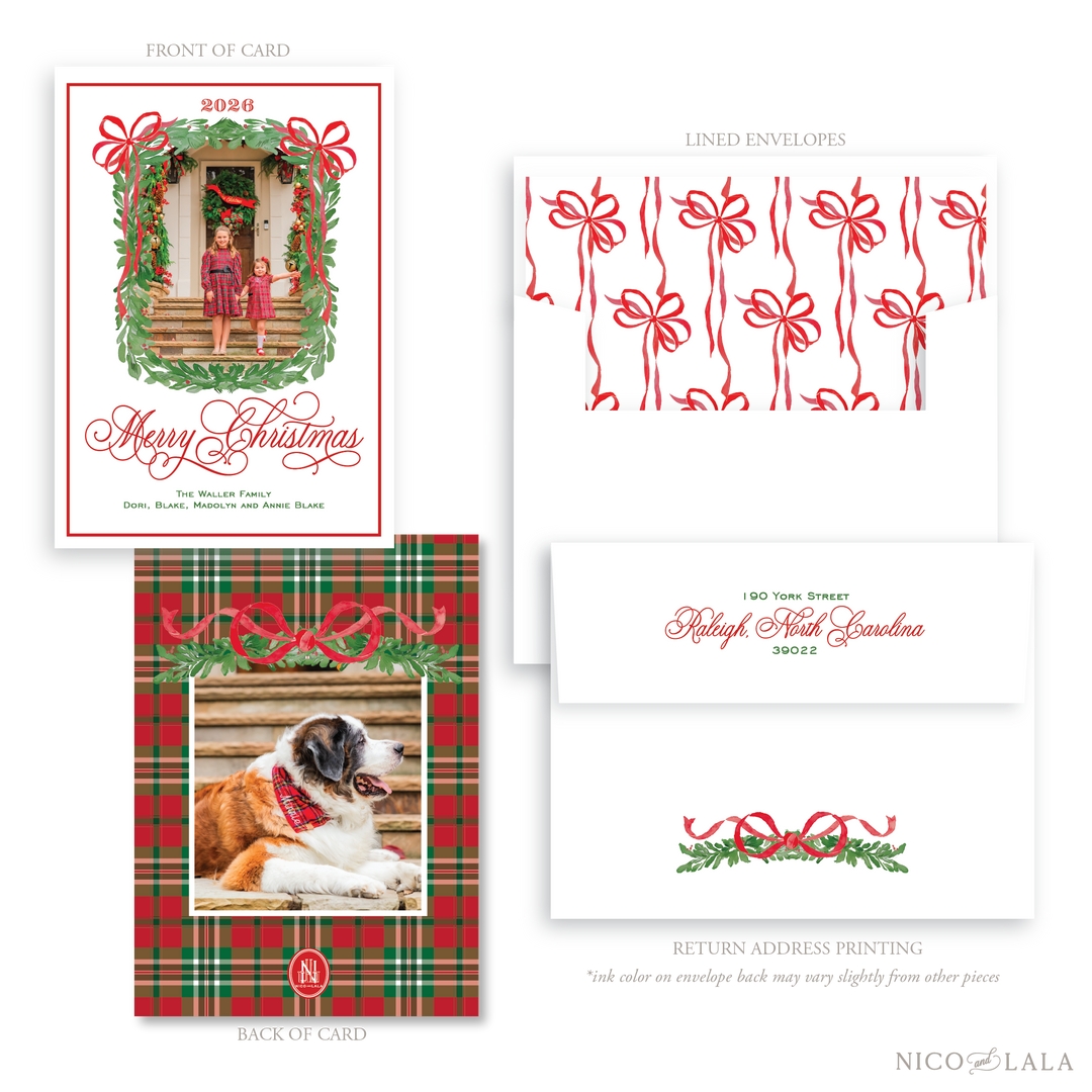 A classic Christmas card and envelope set shown on a white background, with front and back of the card, two lined envelopes, and a return address label. The card features a greenery border around the photo upload area with two red bows. The back of the card has a holiday plaid and greenery illustrations. Envelopes include a liner with red bow patterns and a white envelope.